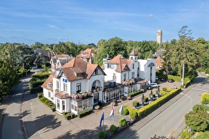 Amrâth Hotel Media Park in Hilversum, lichte gevel met kleurrijke bloemen en buitenzitplaatsen.