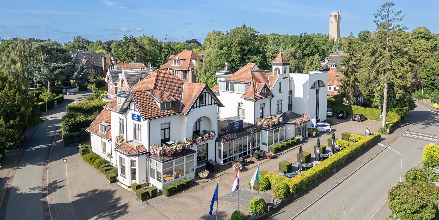 Drone photo of Amrâth Hotel Media Park Hilversum, a characteristic white hotel, located in a green residential area near the center of Hilversum.