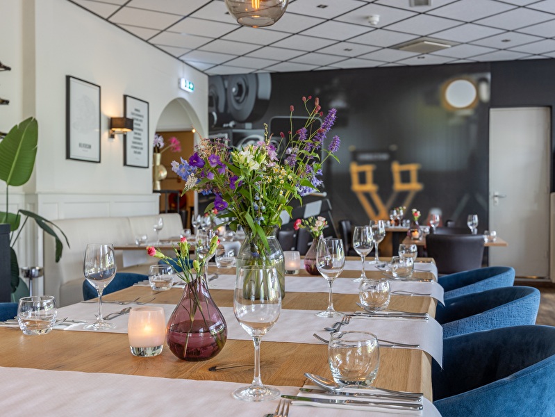 A charmingly set dinner table in the restaurant of Amrâth Hotel Media Park Hilversum with flowers and candlelight.