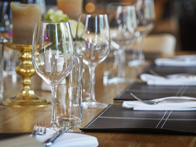Gedekte dinertafel met wijnglazen, waterglazen, bestek en zwart-witte placemats met een gouden kandelaar
