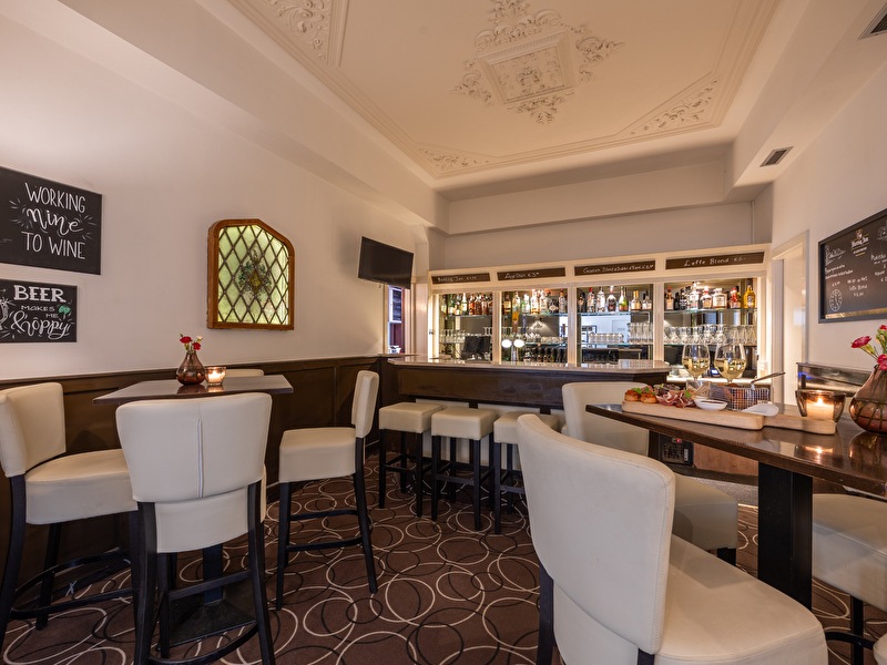 Interior of the bar in the Amrâth Hotel Media Park Hilversum, with a long counter, seating area, and chandelier.