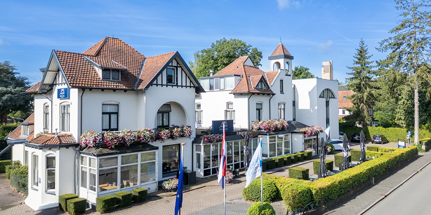 Amrâth Hotel Media Park in Hilversum, light facade with colorful flowers and outdoor seating.