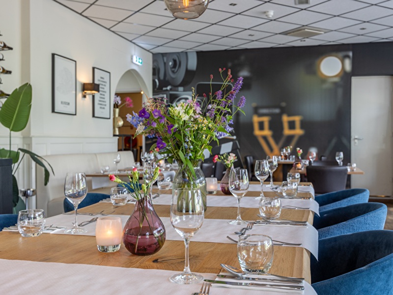 Een sfeervolle restauranttafel met wijnglazen en een kleurrijk boeket bloemen voor een gezellige ambiance.