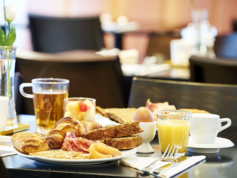 Een ontbijtbord met croissants, brood, vleeswaren, zalm, een gekookt ei, jus d'orange en thee in Amrâth Hotel Media Park Hilversum