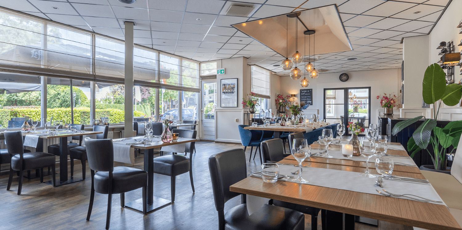 Restaurant in Media Park Hilversum with a striking mural of a recording set and a large dining table with leather chairs