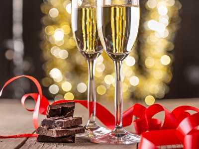 Twee champagneglazen versierd met chocolade en een rode strik, perfect voor een feestelijke gelegenheid.