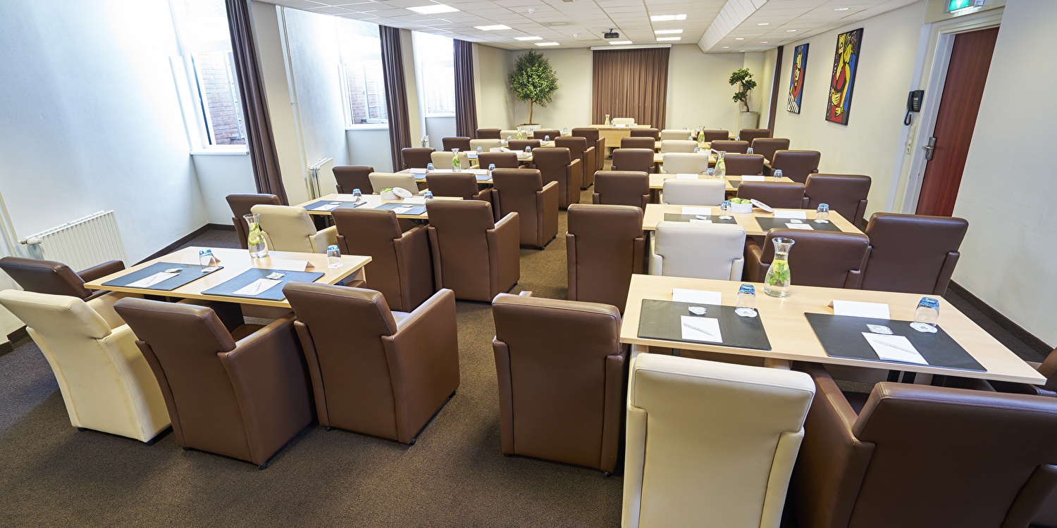 Een vergaderzaal met 2 rijen opstelling voor 2 personen per tafel. 