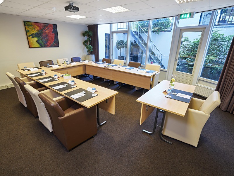 Een grote, lichte ruimte met een centrale tafel , ideaal voor vergaderingen of bijeenkomsten.